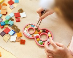 The mosaic puzzle art for kids, children's creative game. The hands are playing mosaic at table. Colorful multi-colored details close up. Creativity, children's development and learning concept